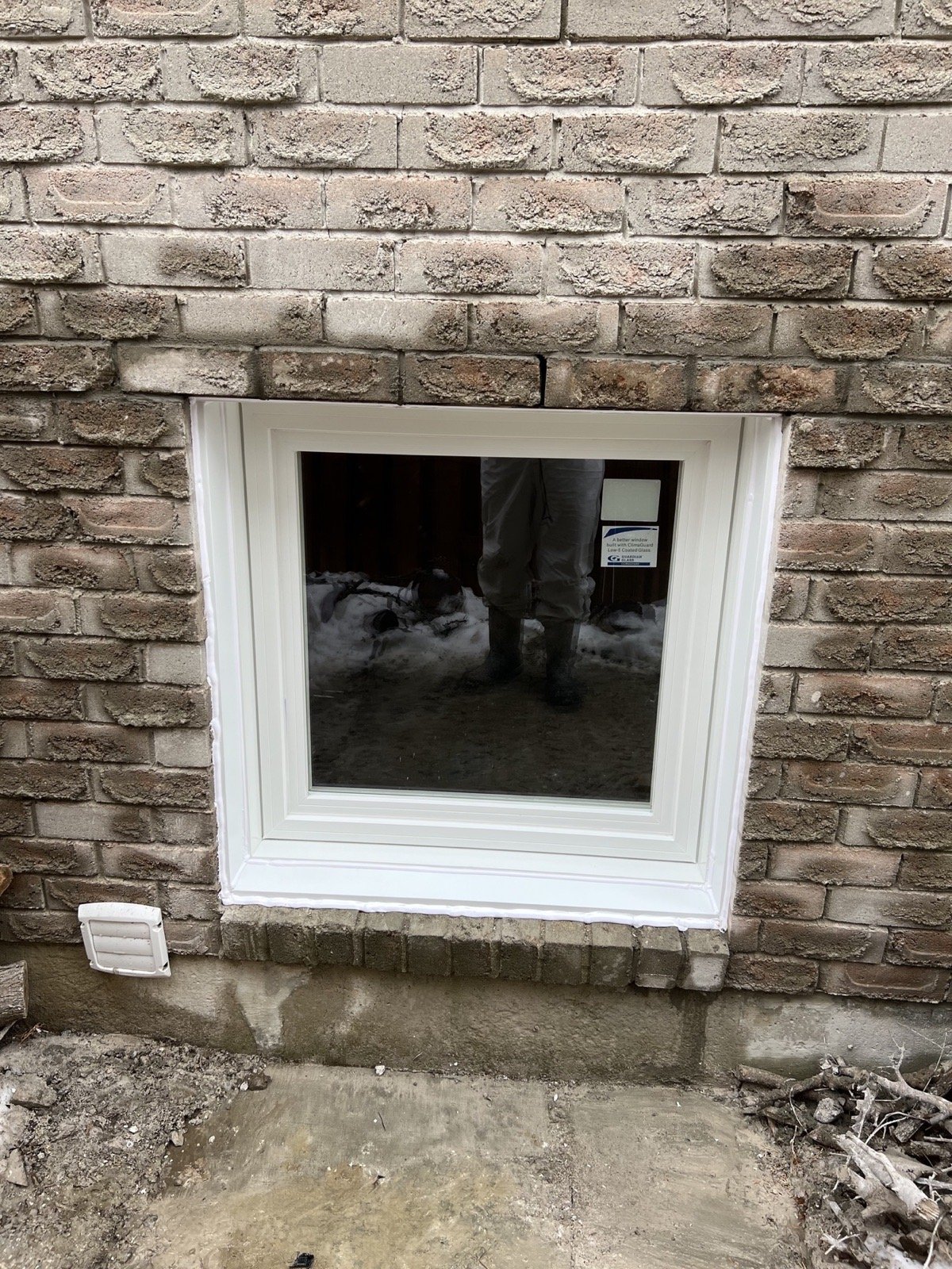 Finished white basement casement window set in masonry