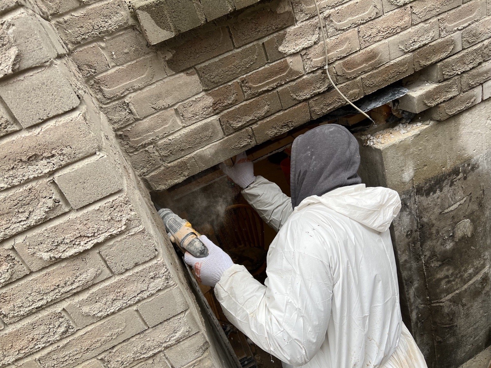 Installer cutting masonry for a larger basement opening