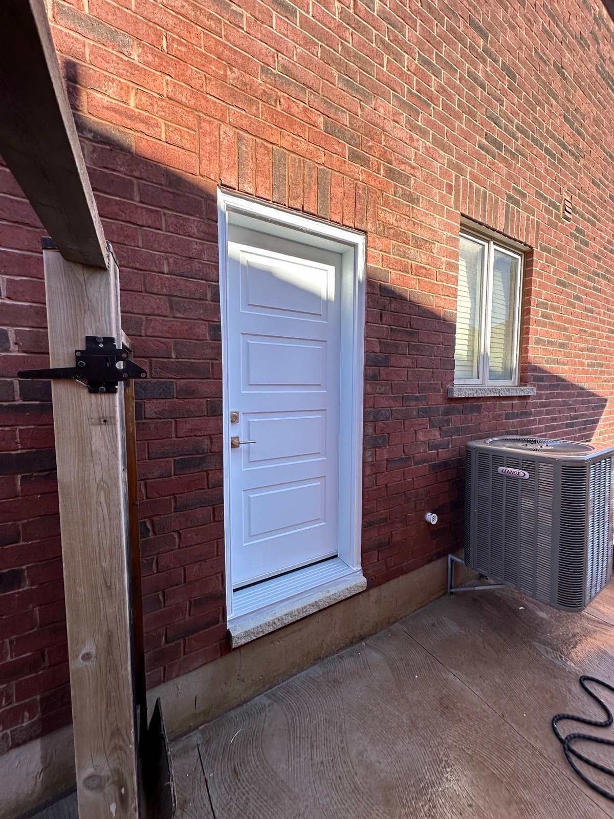 Finished white steel side entrance installed in a Brampton brick wall