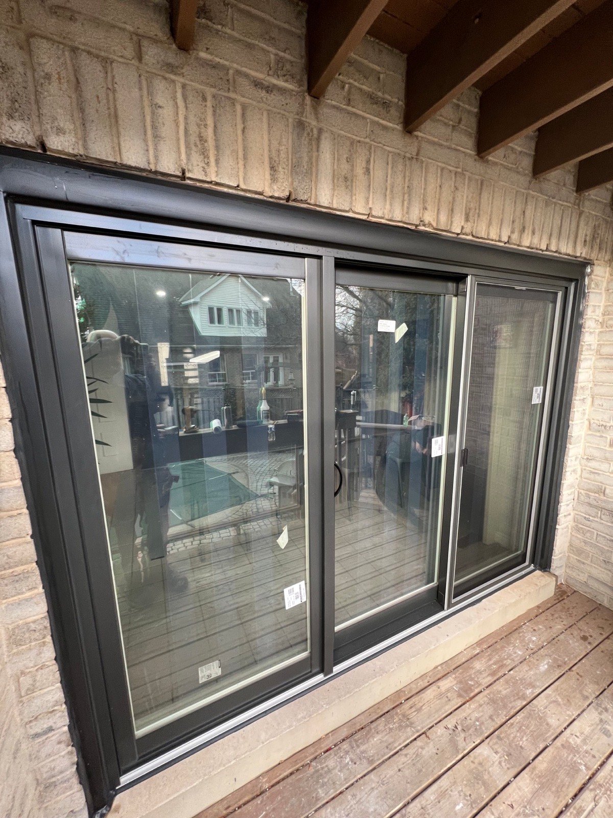 Black sliding patio door installed in a white-brick rear wall