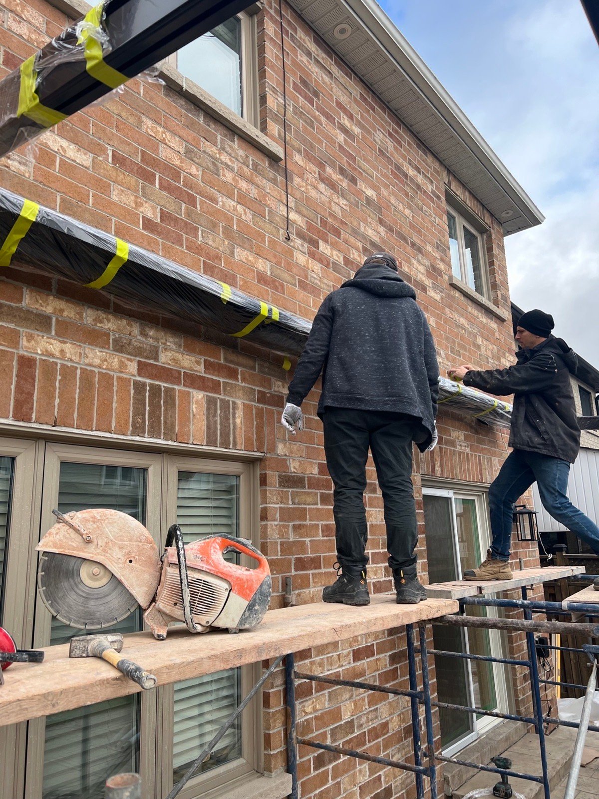 Installers guiding a wrapped steel beam toward a rear wall opening